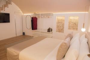 een witte slaapkamer met een groot bed en een televisie bij POSA - Charming Rooms in Acquaviva delle Fonti