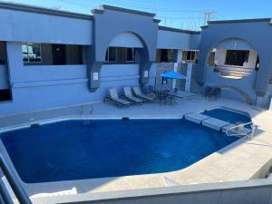 a house with a large swimming pool with chairs and a table at Hotel Senorial in Puerto Peñasco