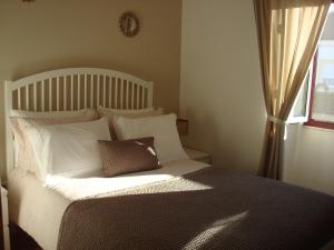 a bedroom with a bed with white pillows and a window at CASA NA ALDEIA in Estremoz +38 photos