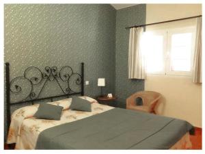 a bedroom with a bed and a chair and a window at Casa Rural Valdevilano in La Roca de la Sierra