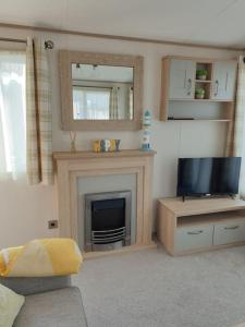 a living room with a fireplace and a television at The Sea Breeze - 8 Berth Premium Caravan in Camber Sands in Camber