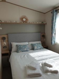 a bedroom with a bed with two towels on it at The Sea Breeze - 8 Berth Premium Caravan in Camber Sands in Camber