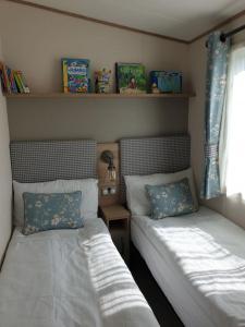 a bedroom with two beds and a window and shelves at The Sea Breeze - 8 Berth Premium Caravan in Camber Sands in Camber +13 photos