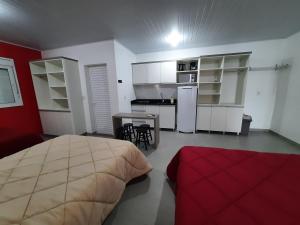 a bedroom with a bed and a table and a kitchen at Galileia flat in Santa Maria