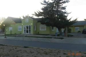 Una casa amarilla con un árbol delante. en Hosteria La casa de Ketty en Puerto San Julián