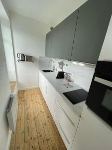 cocina con armarios blancos y suelo de madera en Hyper centre : Appart ancien rénové / tout confort en Clermont-Ferrand