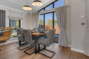 a dining room with a table and chairs and a large window at Dewin Bach - Luxury Lodge, Hot Tub, Close to Beach in Penally