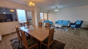 a living room with a table and blue chairs at Midpoint Sea View - families only in Alexandria