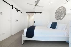 
a bedroom with a white bed and white walls at Centrepoint Apartments Caloundra in Caloundra
