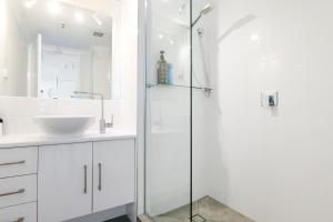 a bathroom with a sink, mirror, and shower at Centrepoint Apartments Caloundra in Caloundra