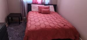 a bed with a red comforter and two pink pillows at Guesthouse, cozy private room in Bronx