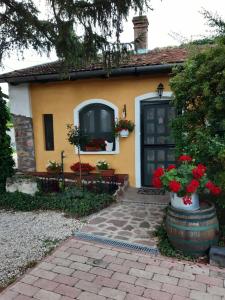 雷夫菲勒普的住宿－Villa-Magdi Vendégház，一间黄色的小房子,有黑色的门和鲜花