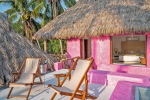 卡熱伊斯的住宿－Bungalows & Casitas de las Flores in Careyes，粉红色的房子,配有两把椅子和一张床