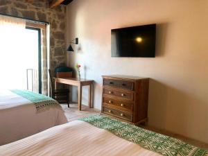 a bedroom with a dresser and a television on the wall at Hotel Casa Xaa in Tlatlauquitepec
