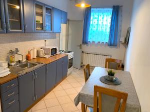 uma cozinha com uma mesa e uma cozinha com armários azuis em Crystal Lakes Apartment em Plitvicka Jezera