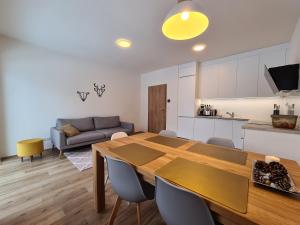 cocina y sala de estar con mesa de madera y sillas en Apartmán Útulnô: Relax, sauna a výberová káva, en Horní Maršov