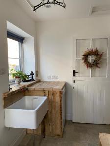 baño con lavabo blanco y ventana en Monawilline Cottage, en Lamlash