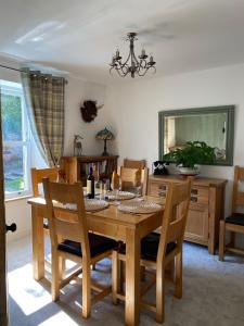 a dining room with a wooden table and chairs at Monawilline Cottage in Lamlash