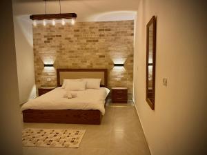 um quarto com uma cama e uma parede de tijolos em Ran suites em Mas'ada