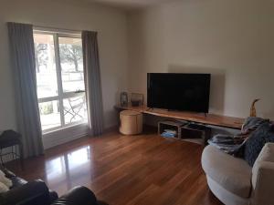 a living room with a couch and a flat screen tv at Woodside Ranch Luxury Farmstay in Woodside