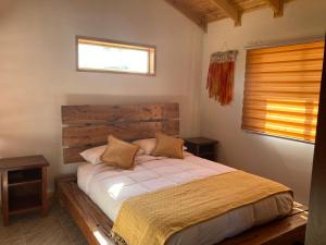 um quarto com uma cama com uma cabeceira em madeira e uma janela em CABAÑA DE CAMPO em Cuncumén