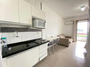 a kitchen with white cabinets and a living room at Angra Praia Grande Flat Studio Angra Inn - O Mar de Angra te espera ! in Angra dos Reis