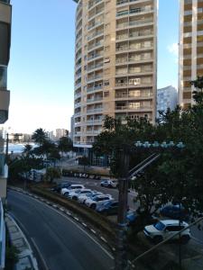 um parque de estacionamento com carros estacionados em frente a um edifício alto em Guarujá Pitangueiras Av Leomil 1515 Ap 22 no Guarujá