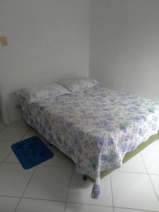 uma cama num quarto branco com um cobertor roxo em Guarujá Pitangueiras Av Leomil 1515 Ap 22 no Guarujá