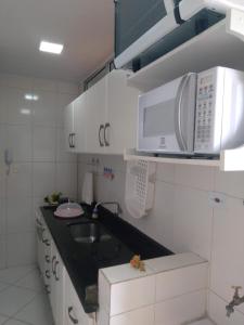 uma pequena cozinha com um lavatório e um micro-ondas em Guarujá Pitangueiras Av Leomil 1515 Ap 22 no Guarujá