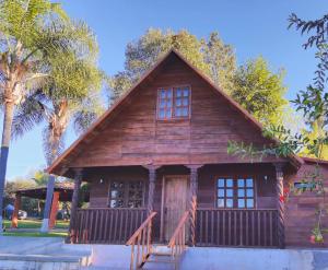 Casa de madera pequeña con porche y palmeras en La Diligencia Cabañas Campestres en Morelia