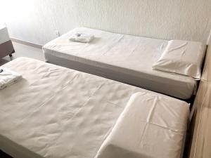 two beds in a room with white sheets at Hotel Premier in Brasilia +4 photos