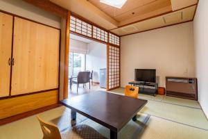 a living room with a table and a television at Daitokan in Kusatsu