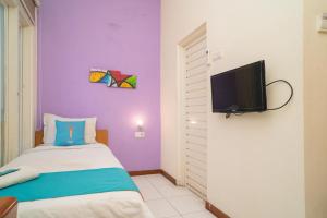 a room with a bed and a tv on a wall at Sans Hotel FiFFa Pisang Kipas Malang in Malang