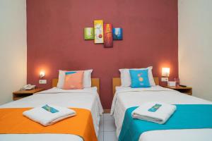 two beds in a room with a red wall at Sans Hotel FiFFa Pisang Kipas Malang in Malang