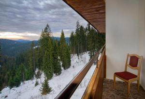 una silla sentada en un balcón con vistas a la nieve bosque cubierto en Kamena Pamporovo, en Pamporovo