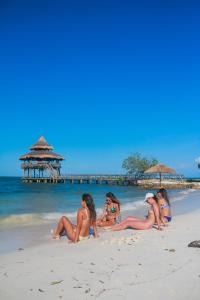 four women in bikinis sitting on the beach at El Embrujo Tintipan in Tintipan Island