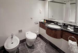 a bathroom with a toilet and a sink and a mirror at Glasgow Grosvenor Hotel in Glasgow