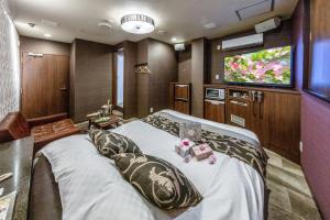 sypialnia z dużym łóżkiem i telewizorem z płaskim ekranem w obiekcie Hotel ＧEM w mieście Sendai