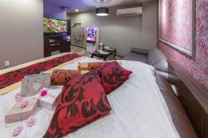 a bedroom with a bed with a red blanket and a television at Hotel ＧEM in Sendai