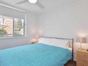 een witte slaapkamer met een bed en een raam bij Shoreline, 4,7 Victoria Parade - Views over Fly Point and close to Nelson Bay Marina in Nelson Bay