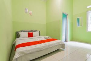 um quarto com uma cama num quarto com paredes verdes em RedDoorz near Tugu Pramuka Cianjur em Bojong 1