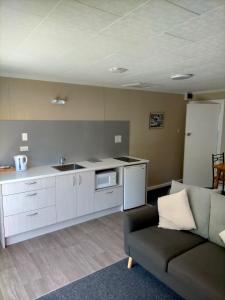a living room with a couch and a kitchen at Arthur's Pass Alpine Motel in Arthur's Pass