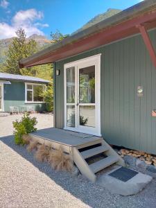 une maison verte avec une porte et une terrasse couverte dans l'établissement Arthur's Pass Alpine Motel, à Arthur's Pass