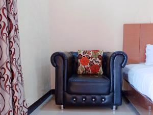 a black chair with a pillow sitting next to a bed at RedDoorz Syariah Near Danau Tes Bengkulu in Tes