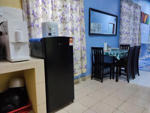 uma cozinha com uma mesa e um frigorífico preto em Riverview Homestay - Homestay Tepi Sungai Golok em Rantau Panjang