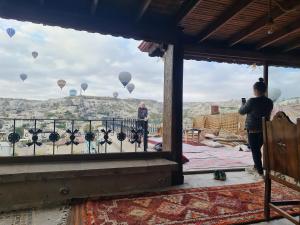 a man standing on a balcony taking a picture of balloons at Vineyard Cave Hotel in Göreme