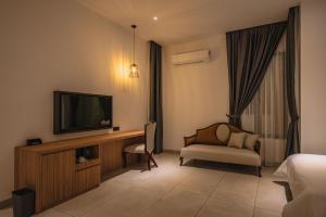 a hotel room with a television and a bed and a chair at Alivila in Muar