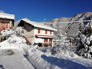 a house covered in snow in front of a mountain at Appartamento tramonto in Abetone