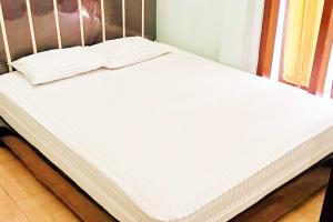 a bed with white sheets on it in a room at Homestay Dieng Persada Syariah Mitra RedDoorz in Dieng