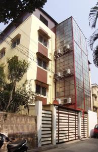 a building with a glass facade with a motorcycle parked in front at Soukyam Hotel in Kolkata